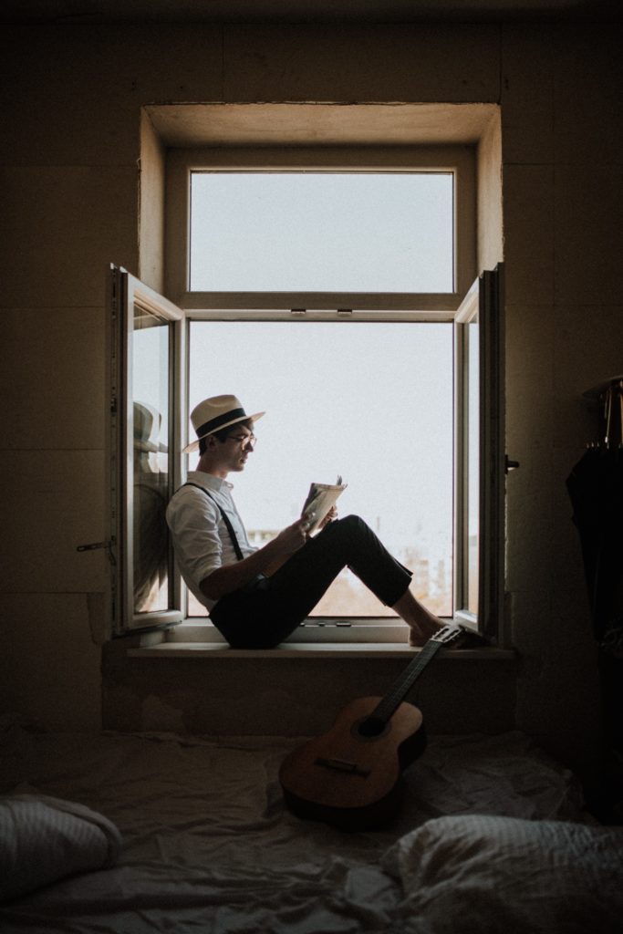 man reading next to a window